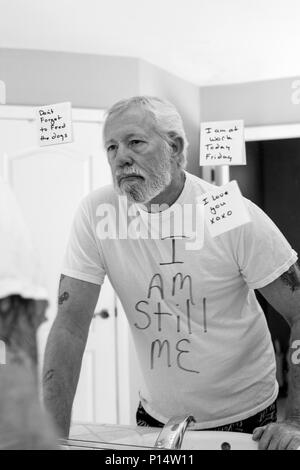 sad man looking in the mirror contemplating his loss of identitiy from dementia Stock Photo