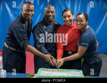 ARABIAN GULF (May 6, 2017) Left to right, Lt. Solomon Lloyd, Command Master Chief Huben Phillips, Aviation Maintenance Administrationman 3rd Class Pauline Dyer, and Hospital Corpsman 3rd Class Terra Lamb cut the cake for Asian American Pacific Islander History Month observance aboard the aircraft carrier USS George H.W. Bush (CVN 77) (GHWB). GHWB is deployed in the U.S. 5th Fleet area of operations in support of maritime security operations designed to reassure allies and partners, and preserve the freedom of navigation and the free flow of commerce in the region. Stock Photo