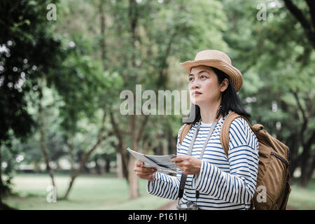 Asian woman backpack traveler use map when traveling at rain forest.Holiday vacation concept.journey lifestyle.solo travel Stock Photo