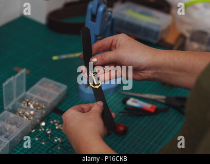 Tanner holds ready-made leather bracelet with decorative anchor in her hands. Process works in the studio close-up. Stock Photo
