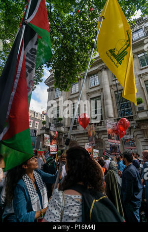 June 10, 2018 - London, UK. 10th June 2018. A woman holds a large Hizbullah flag in the crowd squashed into the street in front of the Saudi Arabian embassy for a rally in support of the oppressed people of Palestine and others around the world.  The flag is used by the political wing of Hizbullah as well as the banned terrorist movement, and so can be flown on UK streets. The event, organised by the Justice for Palestine Committee, is supported by the Islamic Human Rights Commission and a wide range of pro-Palestinian organisations, and was opposed by the Zionist Federation and some right win Stock Photo