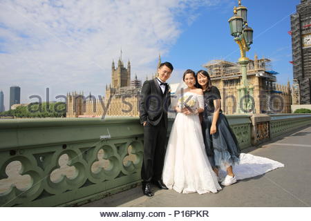 London, UK. 11th June 2018. There was glorious weather in London this morning as early grey skies cleared and brought sunshine to the banks of the Thames. Ideal weather for any one getting married as are Hai and Miao who came to Westminster Bridge with a friend to take wedding photographs. Credit: Clearpix/Alamy Live News Stock Photo