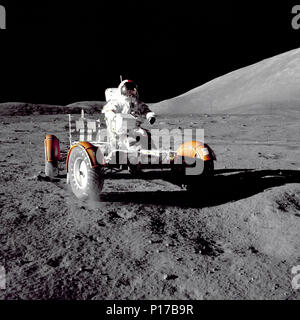 Astronaut Eugene A. Cernan, Apollo 17 mission commander, makes a short checkout of the Lunar Roving Vehicle during the early part of the first Apollo 17 extravehicular activity (EVA-1) at the Taurus-Littrow landing site. This view of the 'stripped down' Rover is prior to loadup. This photograph was taken by Geologist-Astronaut Harrison H. Schmitt, Lunar Module pilot. The mountain in the right background is the East end of South Massif. Stock Photo