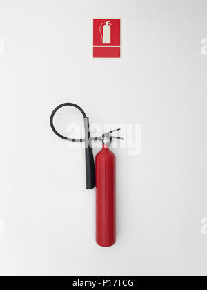 Fire extinguisher with sign alarm on a white wall. Warning Stock Photo