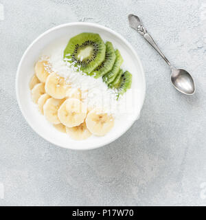 Yogurt bowl with banana, kiwi and coconut. Top view, square crop. Concept of healthy eating, healthy lifestyle, dieting, fitness food Stock Photo