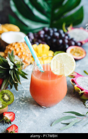 Tropical juice or cocktail in a glass with drinking straw. Closeup view, selective focus Stock Photo