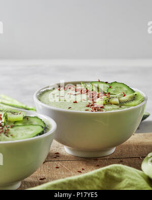 Green smoothies with a cucumber, kiwi and flax seeds in a plate on an old wooden board. Vegetarian food Stock Photo