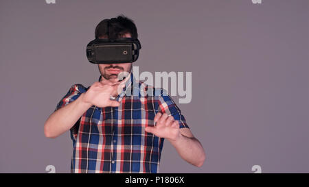 Young man in virtual reality glasses touching an imaginary screen Stock Photo