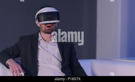 Relaxed smiling man in suit enjoying virtual reality simulator Stock Photo
