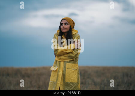 Young girl wearing a yellow raincoat in rainy and cold day Stock Photo