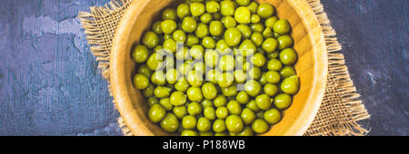Canned peas in a wooden plate on a gray concrete background Stock Photo