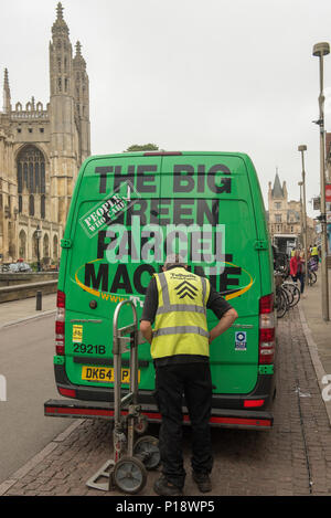 Delivery worker unloads parcels from a green van marked “The Big Green Parcel Machine” near King’s College, Cambridge promoting eco-friendly transport Stock Photo