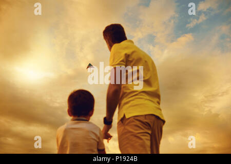 Kite flying in the sky. Father and son playing with a kite at sunset. Stock Photo