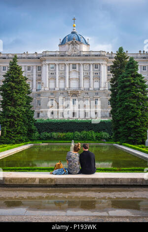 Young people couple, rear view of a young couple sitting in the Jardines de Sabatini on the north side of the Palacio Real in Madrid, Spain. Stock Photo