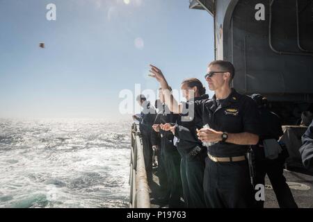 161003-N-BR087-173  PACIFIC OCEAN (Oct. 3, 2016) Lt. Brendan Good, from Talent, Oregon, celebrates Rosh Hashanah by casting bread, symbolizing sin, into the water from USS John C. Stennis' (CVN 74) fantail. Rosh Hashanah is a two-day celebration of the Jewish New Year that provides the opportunity to reflect on the past year and look ahead in the New Year. John C. Stennis is underway conducting proficiency and sustainment training. (U.S. Navy photo by Seaman Cole C. Pielop / Released) Stock Photo