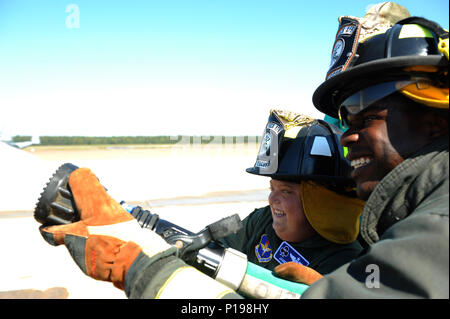 (From right) U.S. Air Force Senior Airman Marcus Scriven, 19th Mission Support Group Fire Department firefighter, helps James Rogers, 17, operate the fire hose during his tour of the fire department Oct. 3, 2016, at Little Rock Air Force Base, Ark. Rogers received the tour as part of the Pilot for a Day program, which provides children who have serious or chronic illnesses an opportunity to be part of a flying squadron for an entire day. Stock Photo