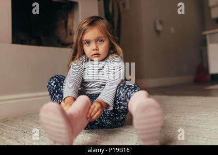 Girl sitting on the floor at home and putting on boots. Stock Photo