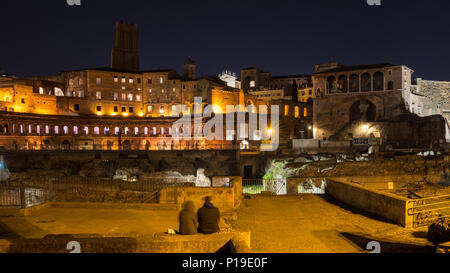 Rome, Italy - March 25, 2018: A couple sit amongst the ruins of Trajan's Forum and Market in Rome at night. Stock Photo