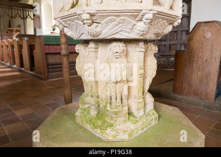 Stone carved lions and angels figures on baptismal font in village parish church of Saint John the Baptist, Butley, Suffolk, England, UK Stock Photo