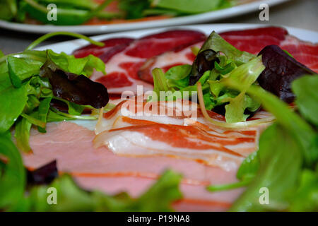Delicious organic food on a wooden plate with olive oil over bread. Ham, salami, peppers,cheese,sausage, salad... Domestic, organic food from Serbia Stock Photo