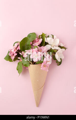 Festive flower apple tree composition in craft horn on the pastel pink background. Overhead view Stock Photo