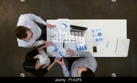 Positive young office employees discussing papers at business meeting Stock Photo