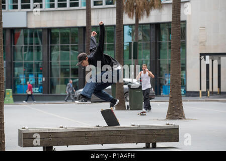 A skateboard rider performs a trick over a bench in Sydney city, Australia Stock Photo