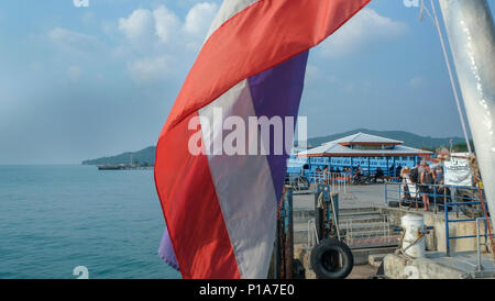 Thai flag over the passengers at a port in Ko Pha-ngan, Thailand Stock Photo