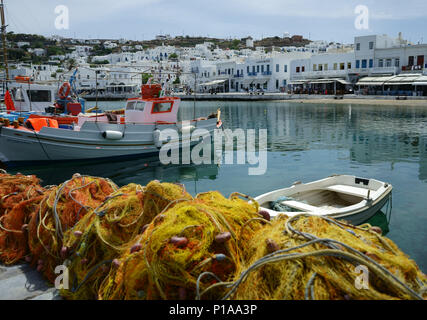 Fishing boats and nets at harbour with towm Mykonos, Cyclades islands,, Greece Stock Photo