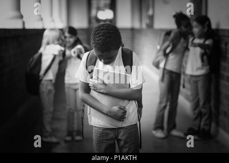 Sad pupil being bullied by classmates at corridor Stock Photo