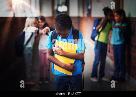 Sad pupil being bullied by classmates at corridor Stock Photo