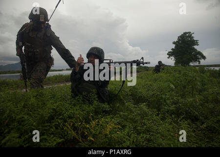 U.S. Marine Cpl. Nicholas Smith checks on Philippine Marine PFC Tali Usman’s security position as they finish the D-Day forcible entry operations on Subic Bay, Philippines, during Philippine Amphibious Landing Exercise 33 (PHIBLEX), Oct. 7, 2016. PHIBLEX is an annual U.S.-Philippine military bilateral exercise that combines amphibious capabilities and live-fire training with humanitarian civic assistance efforts to strengthen interoperability and working relationships. Smith is with Battalion Landing Team, 2nd Battalion, 4th Marine Regiment. Usman is with the Philippine Marine Corps. (U.S. Mar Stock Photo