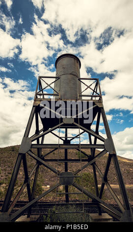 Water tank in the iron structure with the sky and mountain background in the old train station of Zaranda, Spain Stock Photo