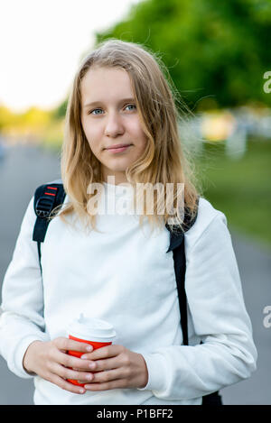 Beautiful girl child blonde. Summer in nature. Holds the hands of coffee hot tea. After breakfast, rest after breakfast. Close-up of beautiful view. Slovenly white hair. Stock Photo