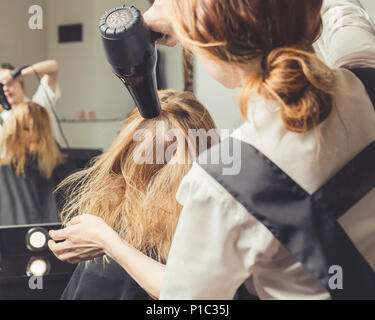 Beautician blow drying woman's hair at beauty salon Stock Photo