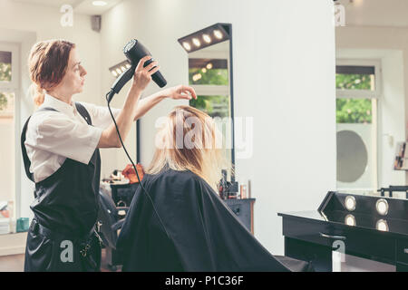 Beautician blow drying woman's hair at beauty salon Stock Photo