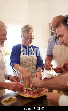 Senior friends making pizza in cooking class Stock Photo