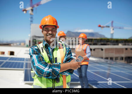 Portrait confident engineer installing solar panels on sunny rooftop Stock Photo