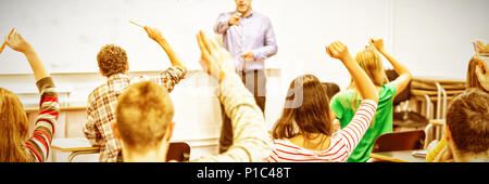 Students raising hands in classroom Stock Photo