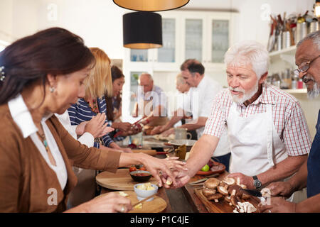 Senior friends making pizza, preparing vegetables in cooking class Stock Photo