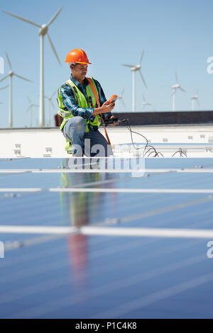 Engineer with equipment inspecting solar panels at sunny power plant Stock Photo