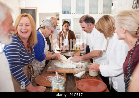 Senior friends enjoying pizza cooking class, making dough Stock Photo