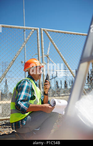 Engineer with walkie-talkie at sunny power plant Stock Photo