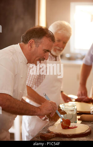 Chef spreading marinara sauce on pizza dough in cooking class Stock Photo