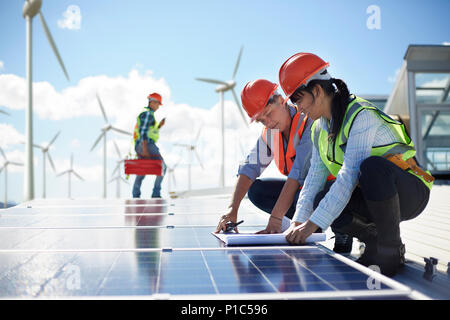 Engineers reviewing blueprints at solar panel at power plant Stock Photo