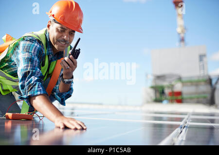 Engineer with walkie-talkie inspecting solar panel at power plant Stock Photo