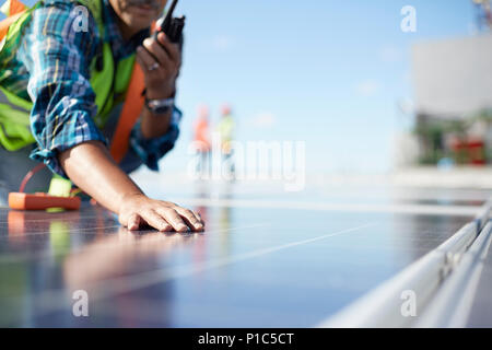 Engineer with walkie-talkie inspecting solar panels at power plant Stock Photo