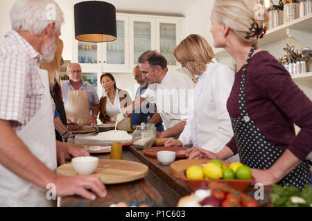 Active senior friends watching chef in pizza cooking class Stock Photo