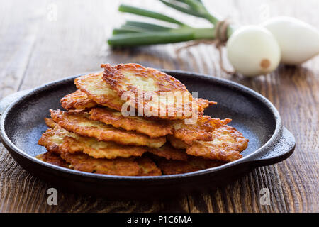Classic Ukrainian dish deruny, potato pancakes in cast iron skillet on rustic wooden table Stock Photo