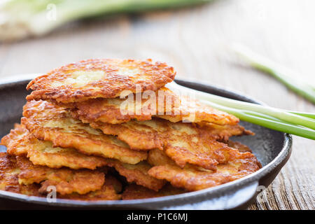 Classic Ukrainian dish deruny, potato pancakes in cast iron skillet on rustic wooden table Stock Photo